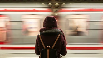 A woman standing alone in front of a fast-riding train