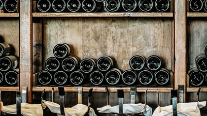 The sophisticated allure of black wine bottles elegantly displayed on a rustic wooden shelf, adding a touch of timeless charm to your wine collection