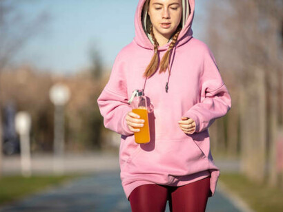 A young woman enjoying an energy drink while exercising in a public park, showcasing the growing trend of energy drink consumption during physical activity