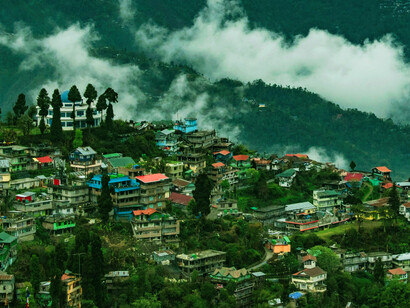 Houses nestled on the lush, sloping terrain of Sonada, Darjeeling, surrounded by velvety tea gardens and a small mountain village, offer a picturesque view of the West Bengal landscape, India