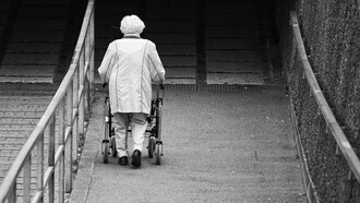 Mujer mayor camina sola por la calle con la ayuda de una andadera