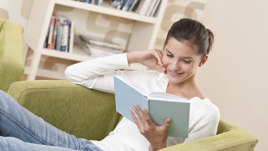 Una chica leyendo un libro en casa