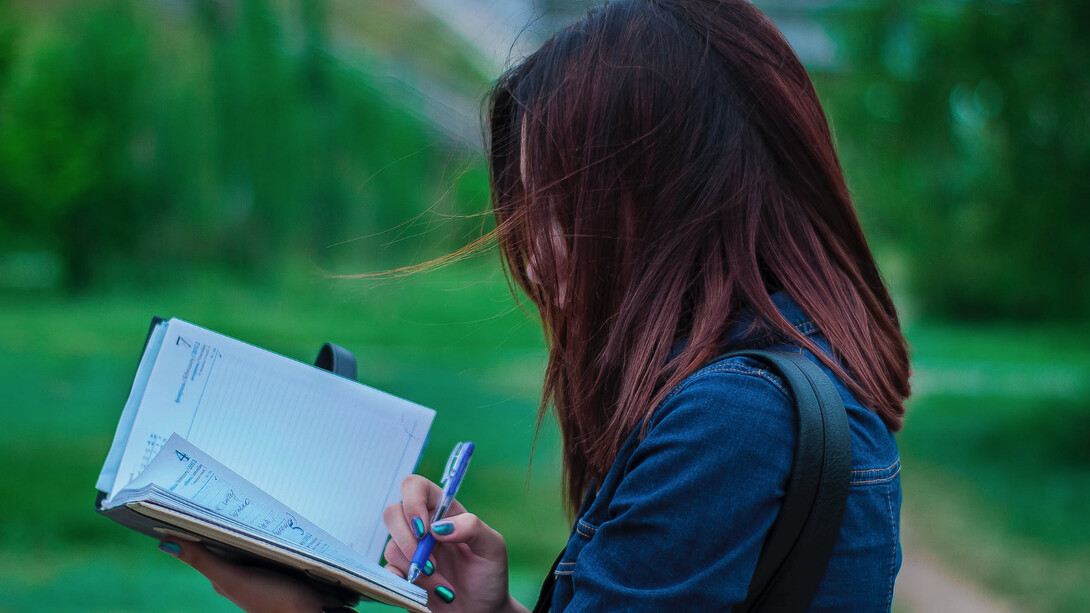 Ragazza scrive su un taccuino all'aria aperta 