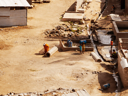 Residents of an informal settlement stand outside their temporary shelters, illustrating the social and economic realities faced by many communities in the Global South