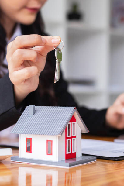 A real estate agent handing over the keys to new homeowners, symbolizing a successful sale and fresh beginnings