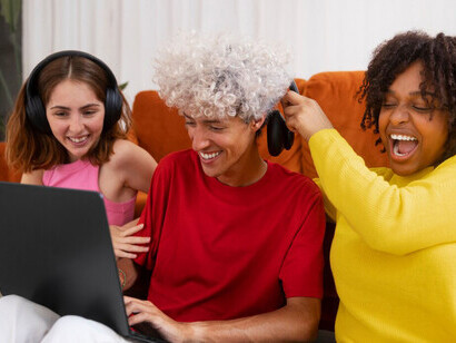A medium shot of friends watching videos on a computer, illustrating the impact of social media and digital platforms on global communication