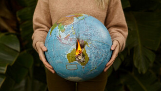 In the palm of a woman's hand, a burning globe symbolizes the urgency of the climate crisis