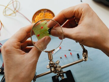 Electronic components being carefully assembled by hand, symbolizing humanity’s attempt to build and control complex intelligent systems