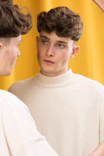 Portrait of a thoughtful boy gazing at himself in the mirror