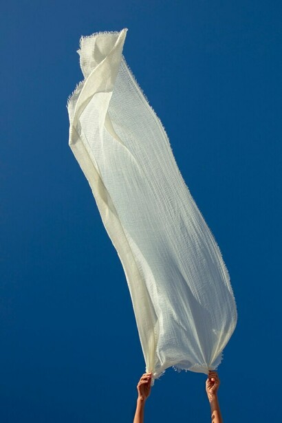 A person waves a fabric in the air, showcasing eco-friendly, biodegradable textiles