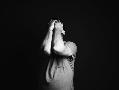 A man with his hands over his face in the midst of depression
