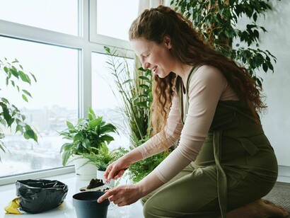 A woman planting seeds in a pot, depicting how even a small home garden can become a reply to the absence of missing ingredients