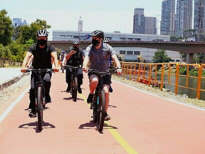 Ciclistas pedalam na ciclovia do Rio Pinheiros em São Paulo, Brasil. As margens do outrora Jurubatuba foram gradativamente comprimidas, vegetação dizimada, passando a abrigar pistas para veículos, trilhos e estações de trens, torres e subestações de eletricidade, ciclovias, trilhas etc
