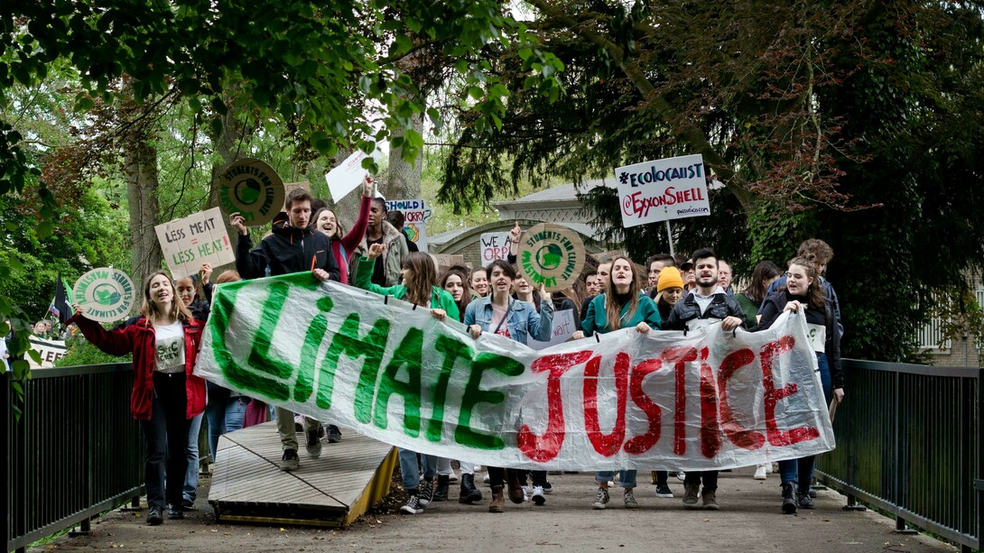 A group of activists marches through the streets carrying banners and signs demanding climate justice during a public demonstration in Maastricht, LI, Netherlands