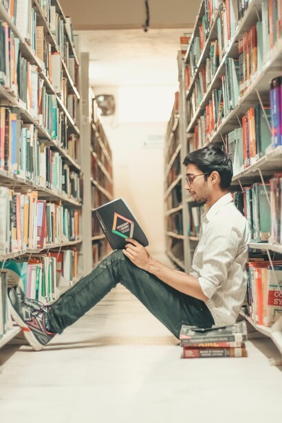 A person sat in a library reading a book