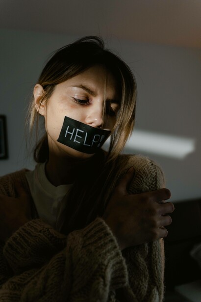 Pensive woman with a help sign taped to her