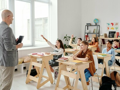 Sala de aula em funcionamento, com estudantes e educador em interação. O espaço onde o ensino acontece, mas nem sempre a aprendizagem se concretiza de forma real
