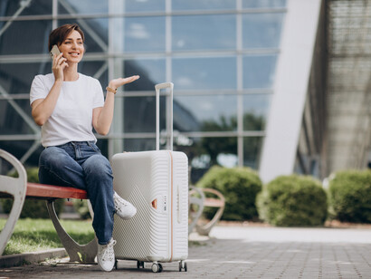 A woman with luggage waits quietly at the airport terminal before boarding her flight