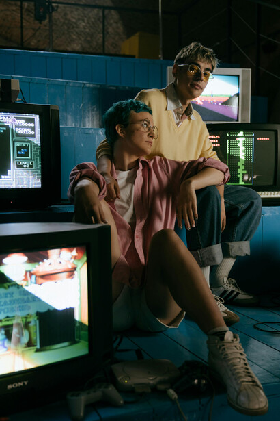 Teenagers sitting next to a TV, playing retro games, surrounded by nostalgic game design
