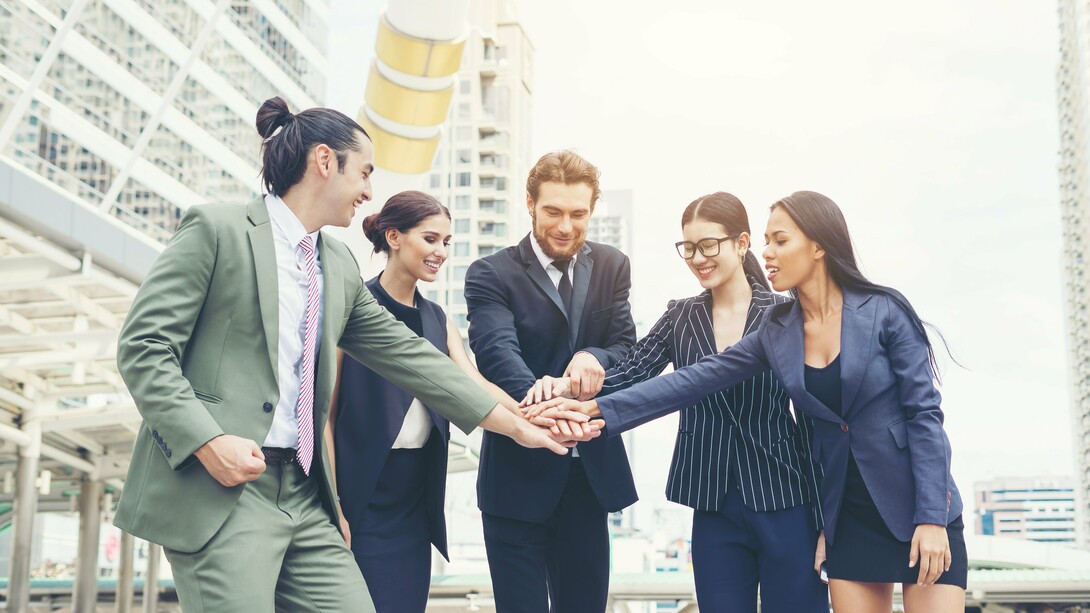 A collaborative team expressing solidarity through joined hands, symbolising the value of collective commitment
