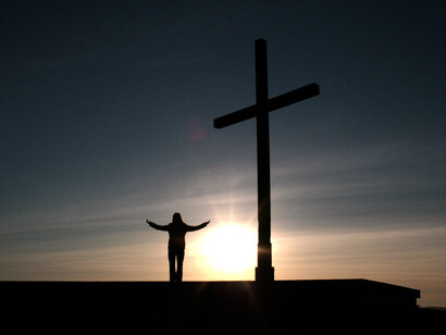 Mientras se pone el sol, una mujer hace alabanzas a una cruz. Atrapada en redes invisibles, busco purificar mi aliento