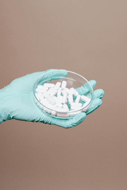 Una mano sosteniendo una placa de petri llena de pastillas. El aumento de enfermedades infecciosas afecta a la salud pública, especialmente en regiones con sistemas de salud ya debilitados