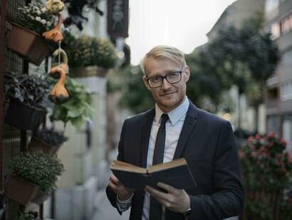 A man in suit displays confidence while reading a book and enhancing his knowledge for a project