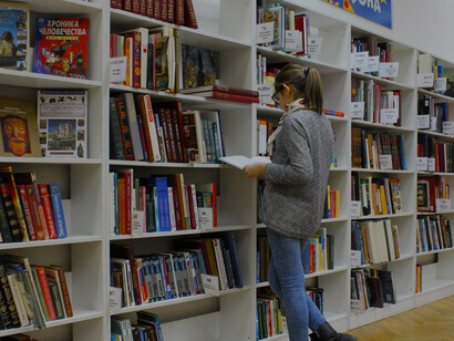 Una joven revisando una biblioteca, buscando qué leer