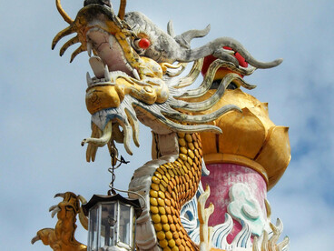 A vibrant Naga-style dragon statue in Thailand is set against a clear blue sky, symbolizing mythological serpent traditions