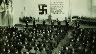 Reunião do partido nazista finlandês SKJ, 1933. Na parede, lê-se: "Libertem o trabalhador da mentira do judaico-marxismo"