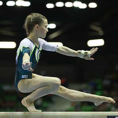 A female gymnast perfecting the balance beam