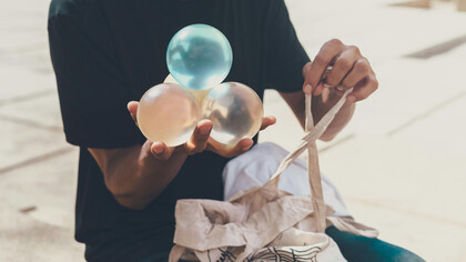 A man holding four juggling spheres on his hand, balancing one on top of the other three