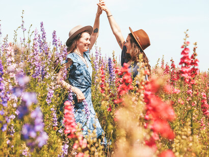 Two friends smile at each other in the flowers, smiles flourish in stern faces, making bodies acquire a special rhythm, that prompts embraces