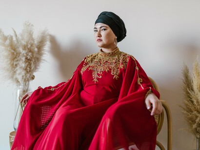 A woman dressed in elaborate red and gold ceremonial clothing, symbolising heritage and tradition expressed through visual symbolism