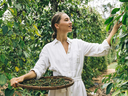 Woman holding a wicker basket full of fresh peppercorns