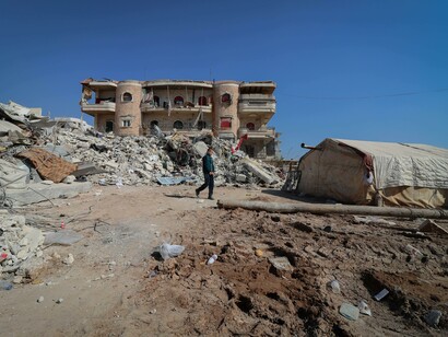 A person walking through the rubble of a city 