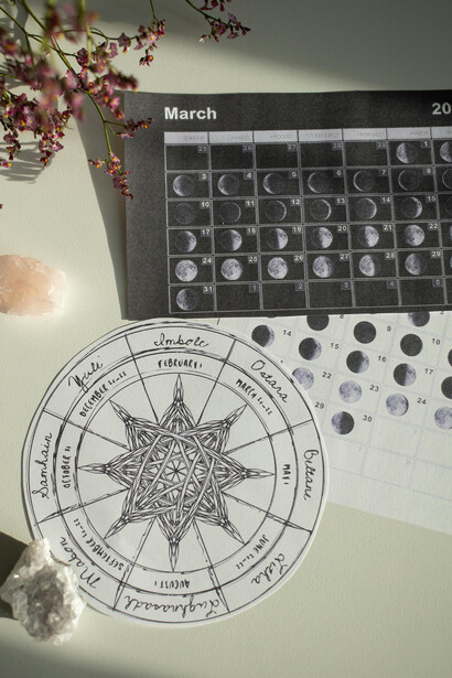 Wheel of the Year and calendar on a white desk