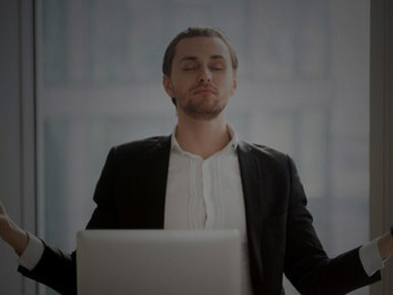 A smiling businessman relaxes in a modern office, practicing anxiety management, stress relief techniques, mindfulness, and breathing exercises to enhance his mental well-being