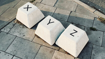 Teclas em formato gigante em meio a calçada. Entenda o conceito de capitalismo de vigilância neste artigo que explora as nossas trocas indefesas com os meios digitais