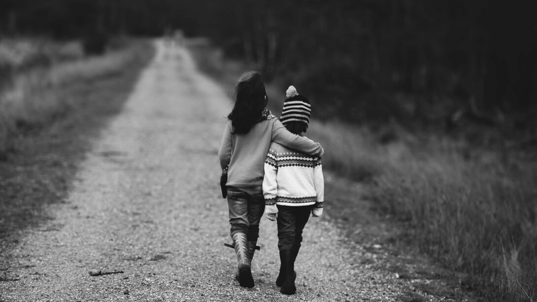 Two kids walking side by side, hugging
