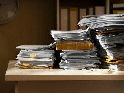 On the table, a stack of documents and papers filled with messy drafts