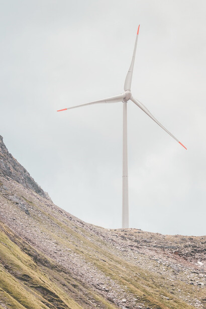 During the daytime, white windmills gracefully stand against the backdrop of a rustic brown field, harnessing the power of wind to generate clean energy