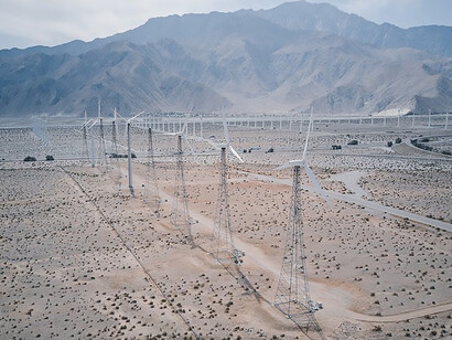 In the vast desert landscape, solar panels rise as beacons of sustainable energy, accompanied by the majestic presence of wind turbines, signifying a dedicated embrace of green energy principles