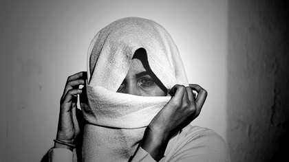 Woman wearing a white hijab, her face veiled with white textile