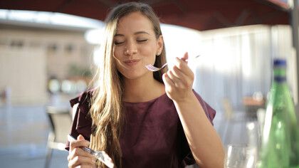 A woman in purple enjoys her meal, taking time to savor each bite