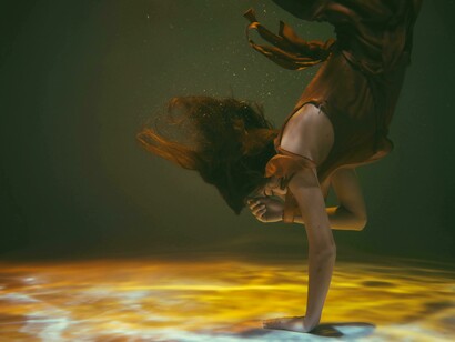 Submerged woman floating underwater, her dress suspended in motion