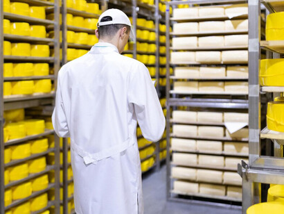 In the dairy factory, a technologist stands, the production line while emphasizing advancements in food supply chain processes, food traceability, and the integration of blockchain technology