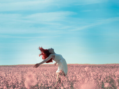 Free-spirited woman breathing fresh air in surrounded by flowers under the sunshine