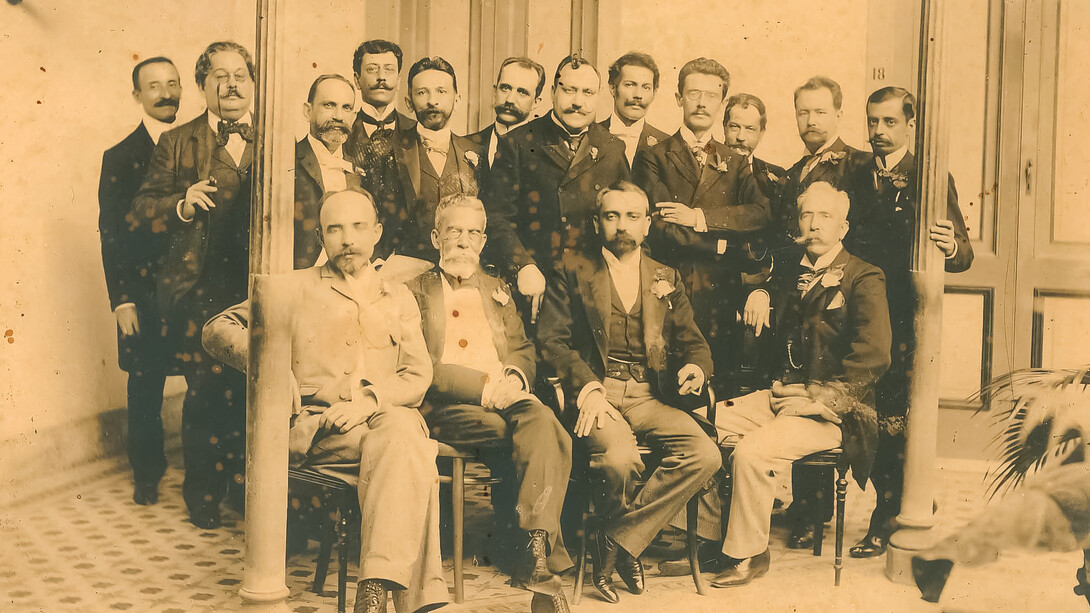 Foto dos integrantes da “panelinha”, criada em 1901 para a realização de festivos ágapes e encontros de escritores e artistas. A fotografia é de um almoço no Hotel Rio Branco (1901), que ficava na Rua das Laranjeiras. De pé: Rodolfo Amoedo, Artur Azevedo, Inglês de Sousa, Bilac, Veríssimo, Bandeira, Filinto de Almeida, Guimarães Passos, Valentim Magalhães, Rodolfo Bernardelli, Rodrigo Octavio, Heitor Peixoto; sentados: João Ribeiro, Machado, Lúcio de Mendonça e Silva Ramos
