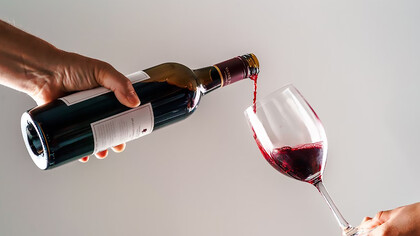 A person gracefully pouring wine into another's hand, capturing the essence of hospitality and shared enjoyment